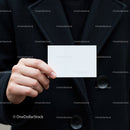 Person holding blank white business card in black coat