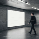 Businessman walking past large illuminated blank billboard