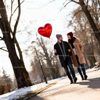 Couple Walking Outdoors with Heart Shaped Balloon in Winter