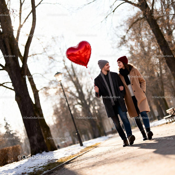 Couple Walking Outdoors with Heart Shaped Balloon in Winter