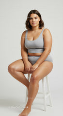 Confident Plus Size Woman Sitting on a Stool in Casual Gray Tank Top