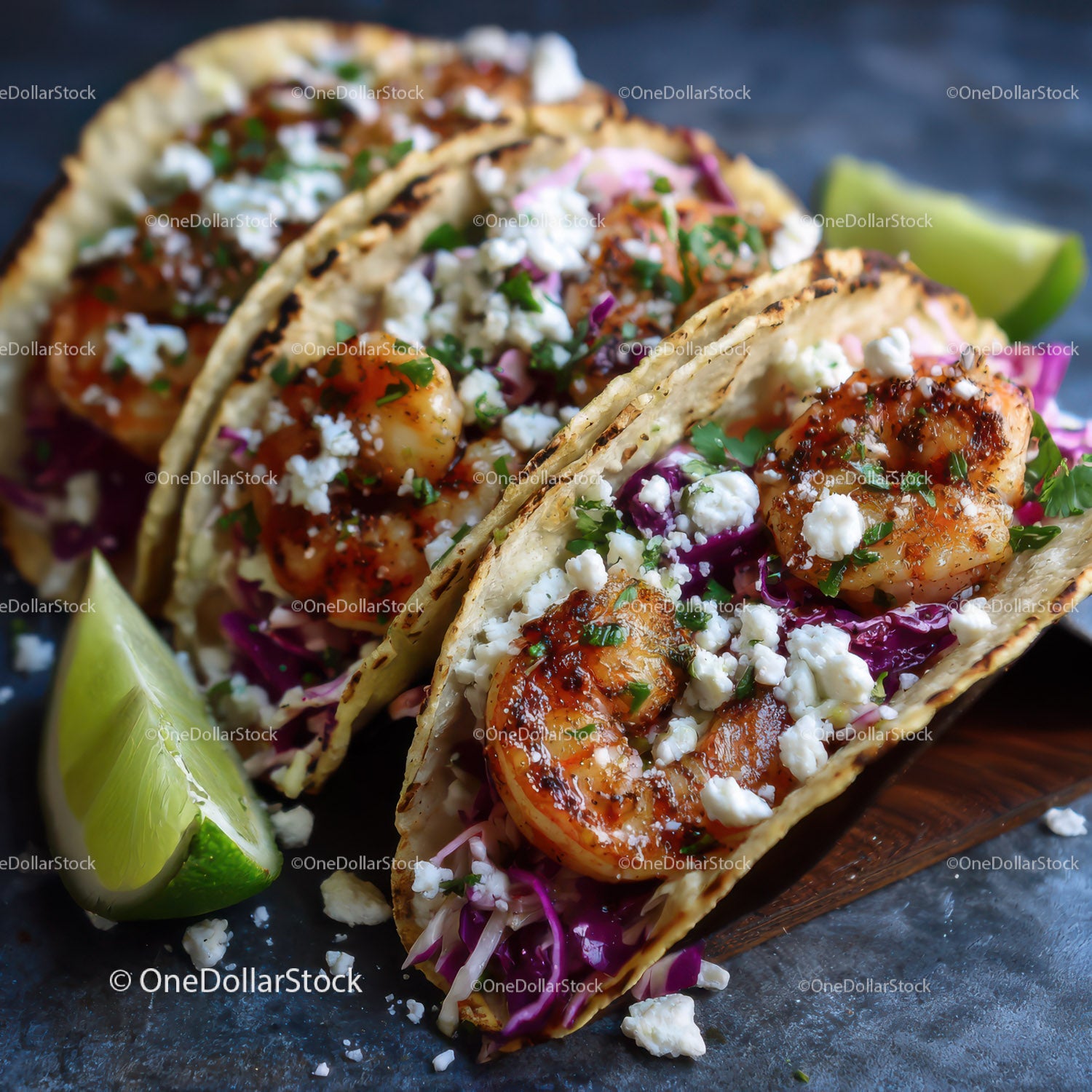 Fresh shrimp tacos with purple cabbage and lime wedges