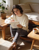 Young woman sketching in cozy natural light at home