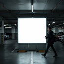 Man walking past illuminated billboard in parking garage