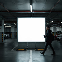 Man walking past illuminated billboard in parking garage
