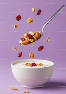 Spoon with granola and nuts over bowl of yogurt