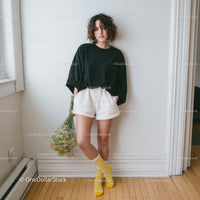 Young Woman in Black T-Shirt and White Shorts Holding Daisy Flowers