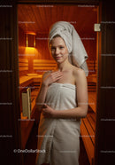 Young Woman Relaxing in Sauna With Towel Wrap and Warm Atmosphere