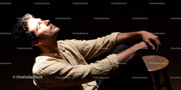 Thoughtful man in warm light against dark background