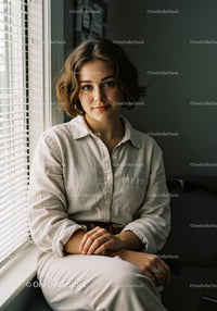 Young Woman in Casual Outfit Sitting by Window with Natural Light