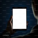 Person Holding Illuminated Digital Tablet in Dark Room