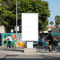 Blank urban billboard with cyclists passing vibrant mural