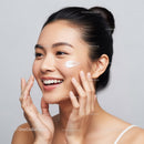 Young Woman Applying Facial Cream with Bright Skin and Glowing Complexion