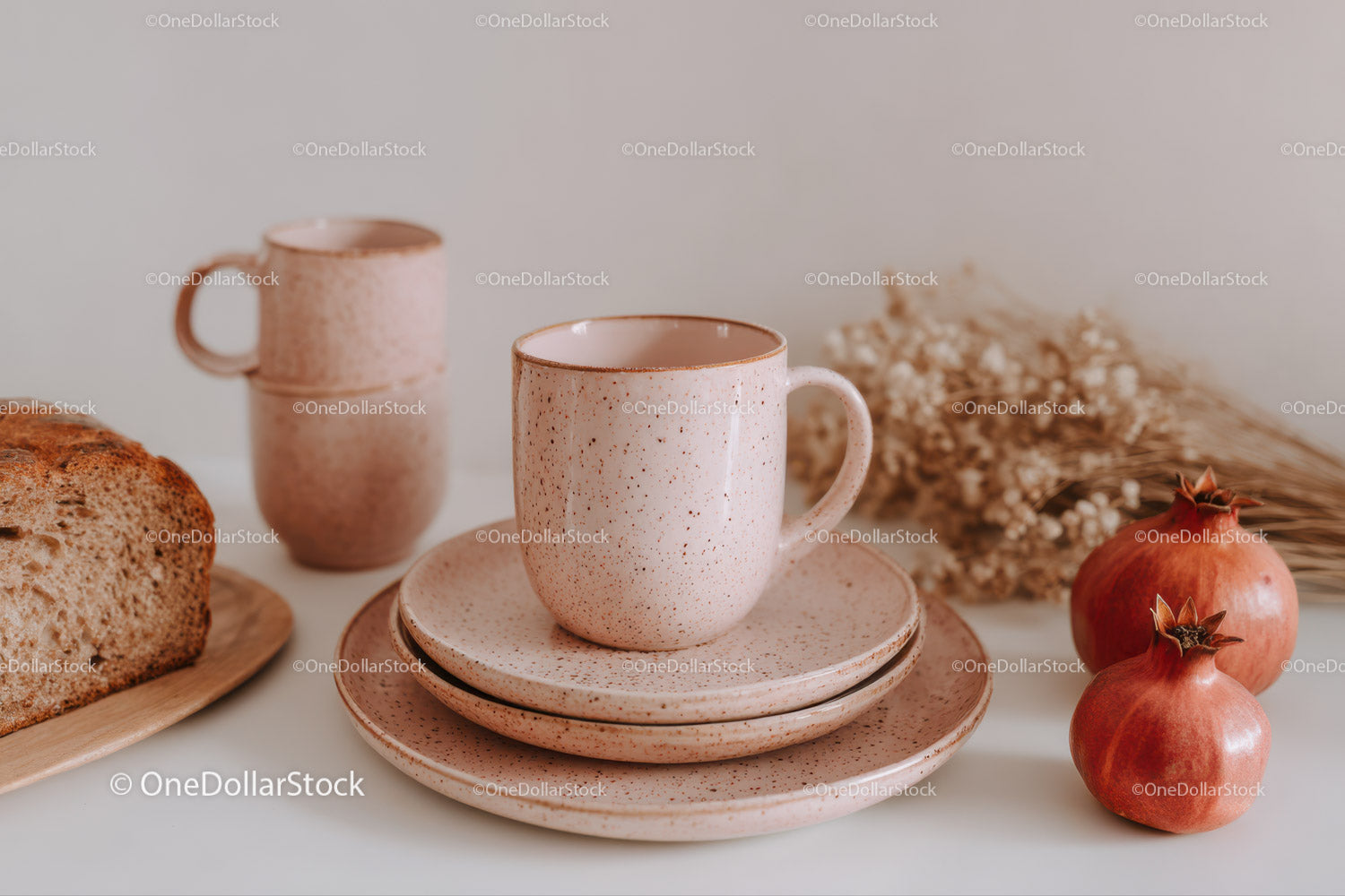 Ceramiczny kubek w kropki z talerzykami, chlebem, suszonymi kwiatami granatu