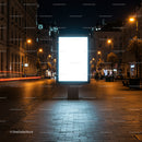 Illuminated blank billboard on city street at night
