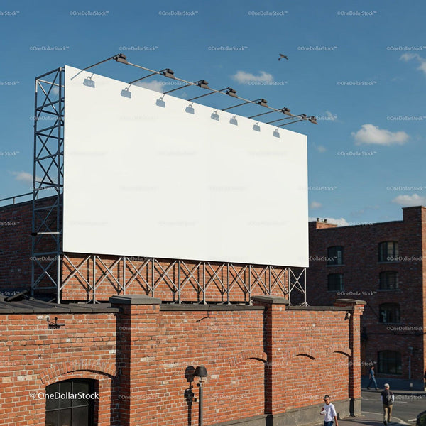 Large blank billboard mounted on brick building under blue sky JPG Mockup Image