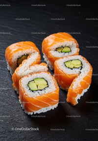 Fresh salmon sushi rolls with avocado on black slate