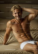 Smiling muscular man relaxing on beige bed in white underwear