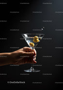 Hand Holding Classic Martini Glass with Olives