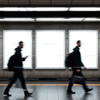 Blurred commuters walking past empty urban billboards