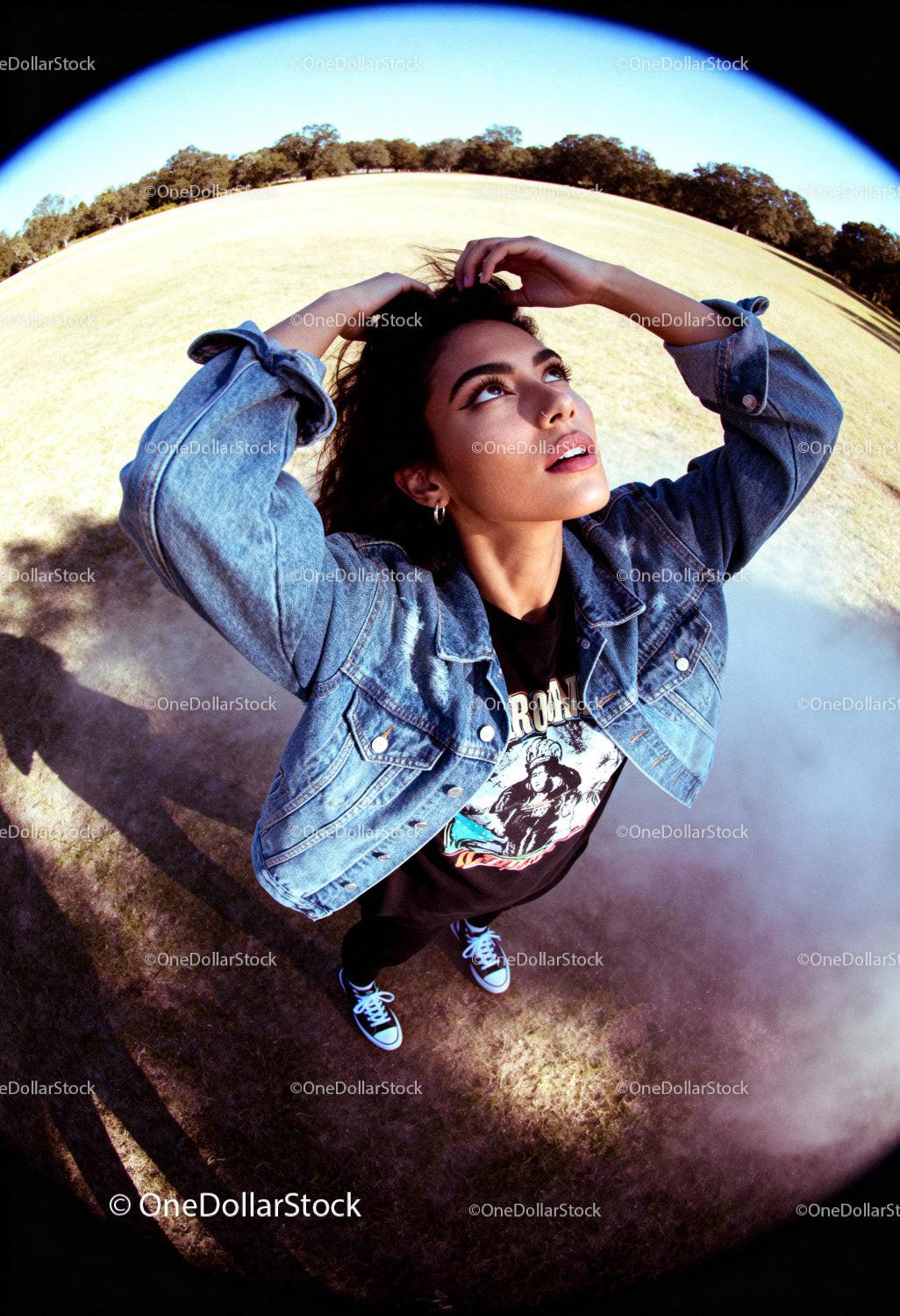 Young woman in denim jacket looking up outdoors