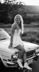Smiling woman in white dress with roller skates on vintage car