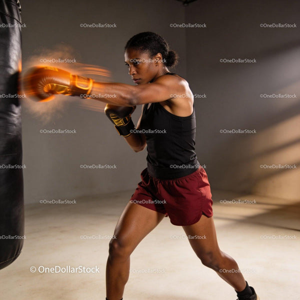 Focused woman training with punching bag in gym