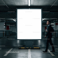 Blurred businessman walking past blank billboard in parking garage