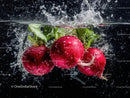 Fresh Radishes Splashing into Water with Leafy Greens in Black Background