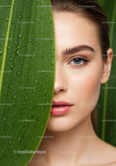 Close-up of a Woman with Blue Eyes and a Green Leaf with Water Droplets