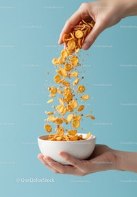 Hand Pouring Cornflakes Into White Bowl On Blue