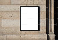 Blank poster frame on textured stone wall outdoors