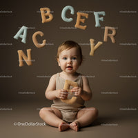 Toddler Sitting with Soft Alphabet Letters on Brown Background