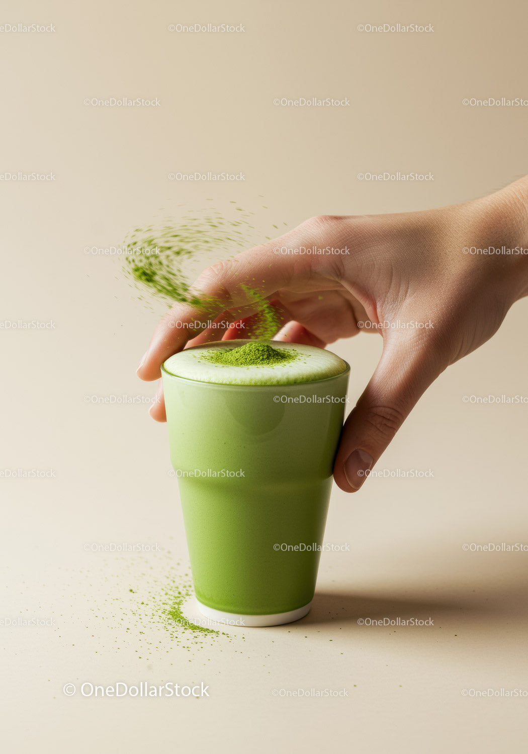 Hand Sprinkling Matcha Powder on Frothy Green Tea Latte