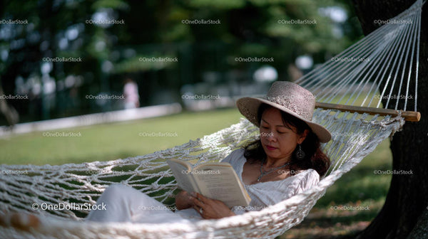 Relaxing Woman Reading Book in Hammock in Sunny Garden