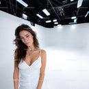 Young Woman in White Dress Holding Confident Pose in Studio