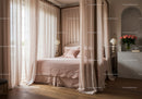Elegant canopy bed with soft pink linens in cozy room