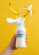 Hand Holding Banana Yogurt Drink with Splash on Yellow