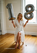 Young woman celebrating 18th birthday with silver balloons