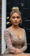 Confident woman in patterned dress sitting by black door