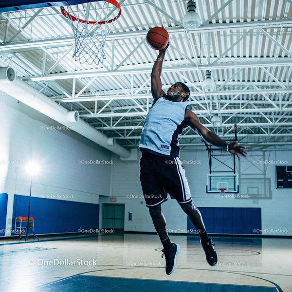 Athlete Jumping to Score a Basketball Dunk