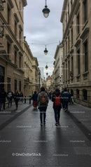 People Walking Along Historic City Street with Overcast Sky