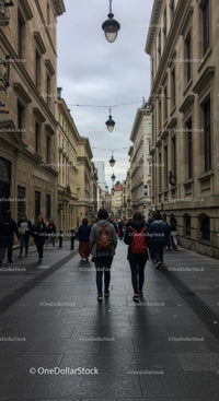 People Walking Along Historic City Street with Overcast Sky