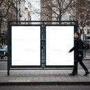 Man walking past empty city billboard on autumn street