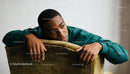 Thoughtful young man resting on green velvet chair