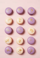 Purple and cream macarons with gold decoration on pink