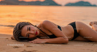 Elegant Woman in Black Bikini Lying on Beach at Sunset