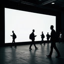 Silhouetted People Walking by Large Bright Screen