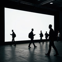 Silhouetted People Walking by Large Bright Screen