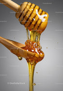 Golden honey flowing from wooden dipper to spoon